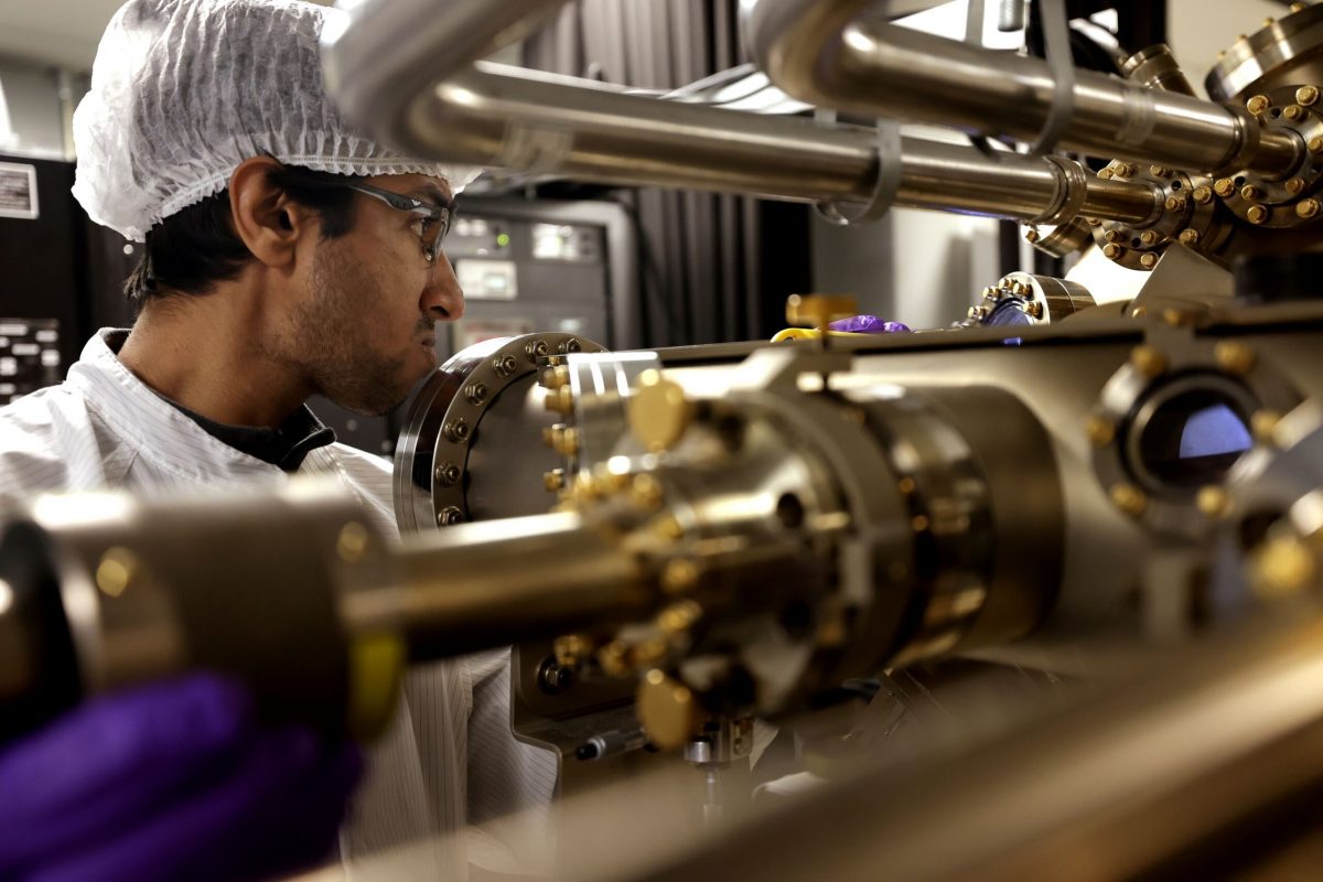 Peng Zhou, right, and Yuyang Pan, first year PhD student, observe the machine in which the semiconductor nanowires are grown. Image credit: Brenda Ahearn/Michigan Engineering, Communications and Marketing