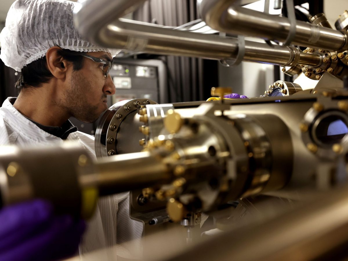 Peng Zhou, right, and Yuyang Pan, first year PhD student, observe the machine in which the semiconductor nanowires are grown. Image credit: Brenda Ahearn/Michigan Engineering, Communications and Marketing